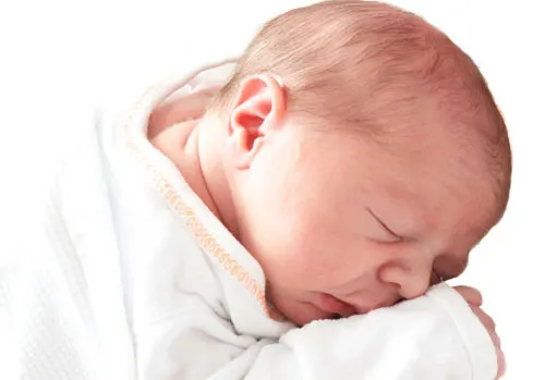 Newborn sleeping wrapped in a white blanket