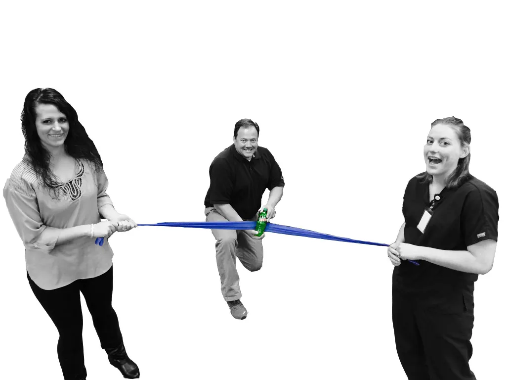 Three staff members acting out a race with a finish-line ribbon