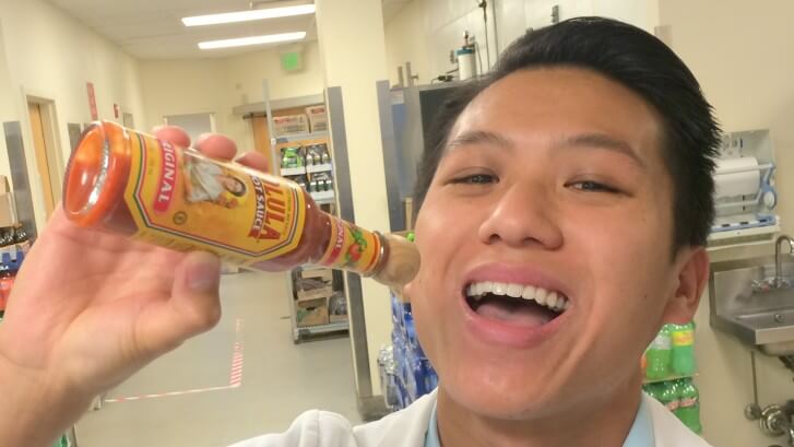 man posing drinking hot sause