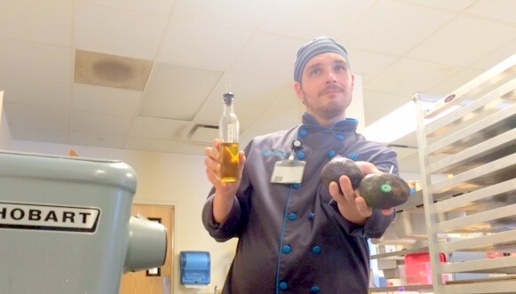 man posing holding avocados and olive oil