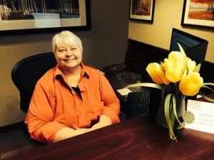Madisonhealth staff member at her desk beside a vase of yellow tulips