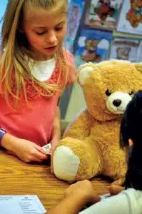 Girl bandaging a teddy bear's arm at a children's activity table