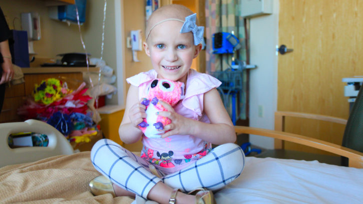 small child holding stuffed animal in hospital bed