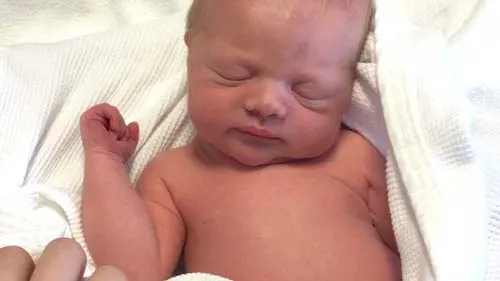 Newborn sleeping wrapped in a white blanket