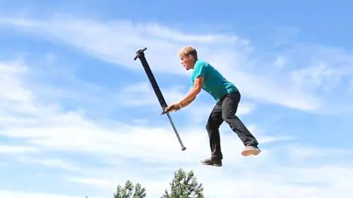 Hiker with a walking pole striding against a bright sky