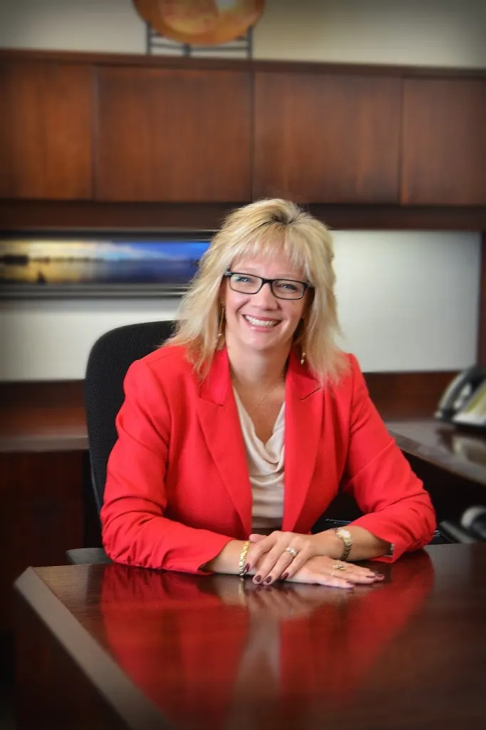 Madisonhealth staff portrait: woman in a red blazer at her desk