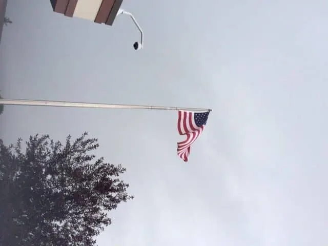 American flag flying at half mast against a cloudy sky