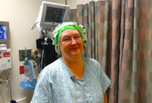 Patient in a gown and surgical cap smiling before a procedure