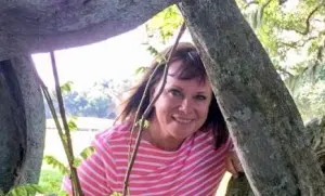 Woman in a striped top sitting in the branches of a tree