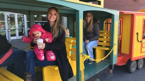 Mother and daughter riding a colourful trackless train at the hospital