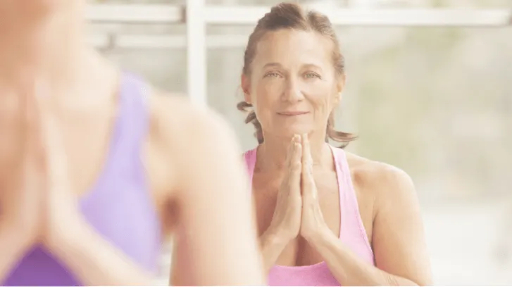 Two women pressing their palms together during a yoga class