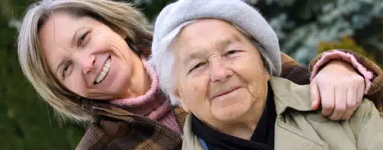 Young woman with her arm around an older woman outdoors