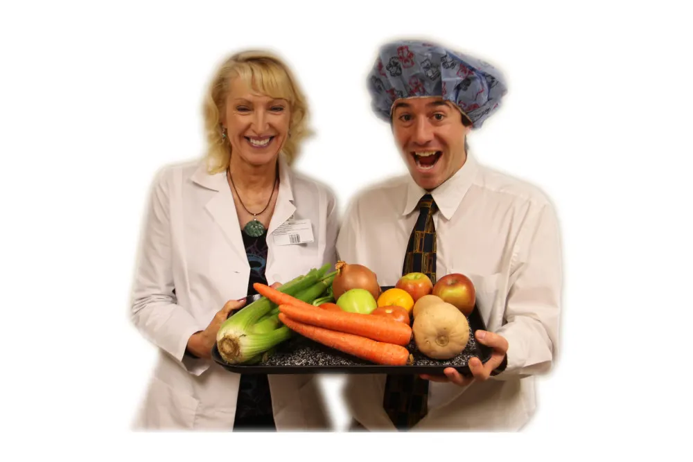 Two staff members holding a tray of fresh vegetables