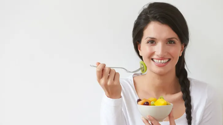 Woman eating a bowl of fruit salad