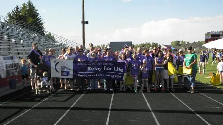Relay For Life participants holding a banner on a running track