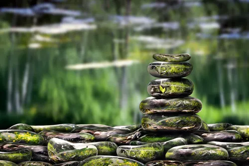 Stacked zen stones resting beside a pond