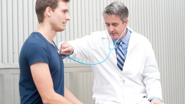 Doctor listening to a young man's chest with a stethoscope