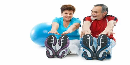 Older couple stretching on the floor with an exercise ball