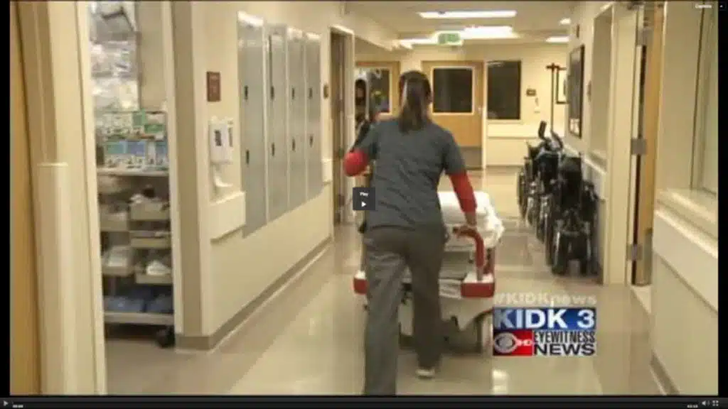 News footage of a staff member pushing equipment down a hospital corridor