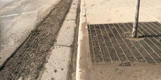 Dirt swept along a kerb beside a storm drain