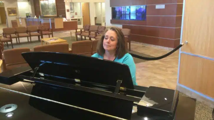 Woman playing a grand piano in the hospital lobby