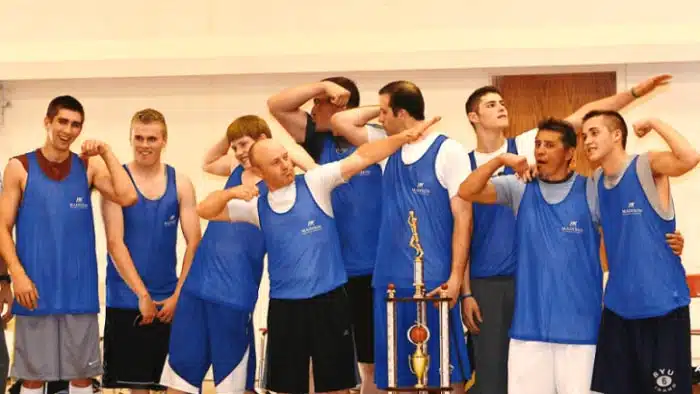 High school basketball team flexing beside their trophy