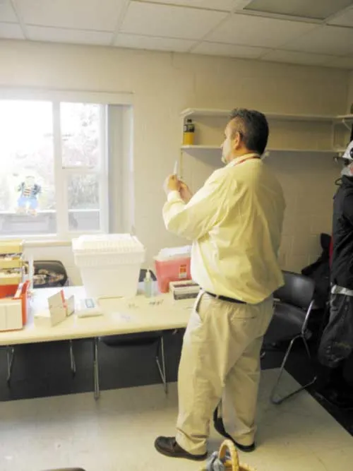 Staff member setting up supplies at a table in a clinic room