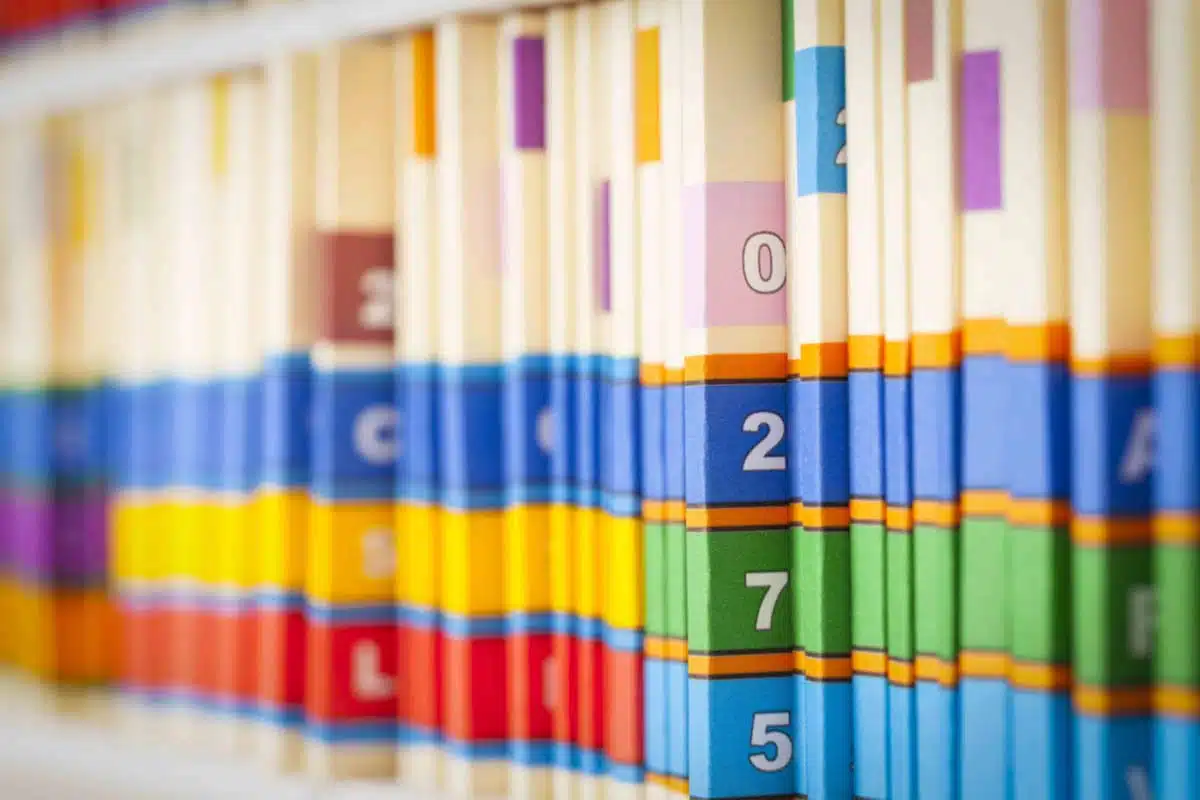 Row of colour-coded patient record files on a shelf