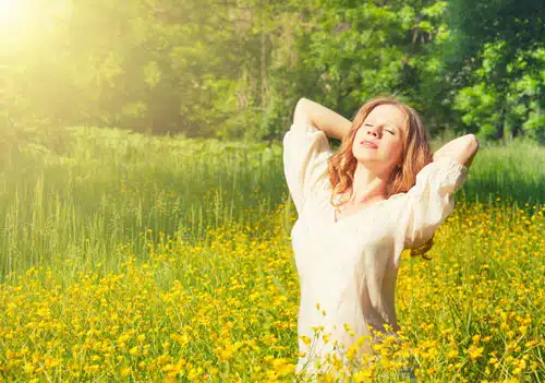 Woman stretching in a sunlit meadow of yellow flowers