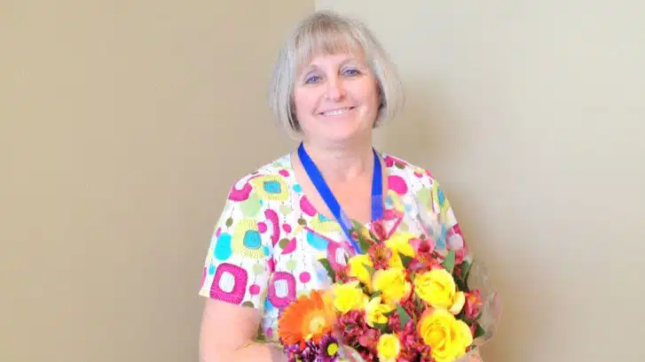 Madisonhealth staff member in patterned scrubs holding a bouquet