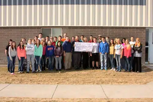Large group of students holding a cheque outside a school