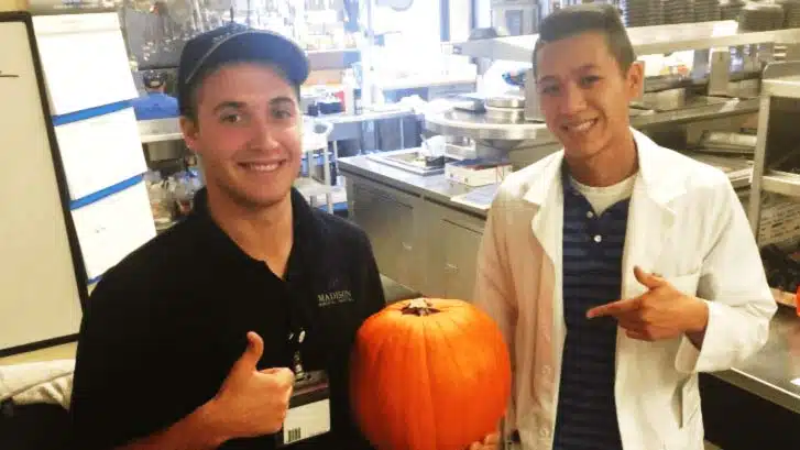 Two kitchen staff members holding a pumpkin