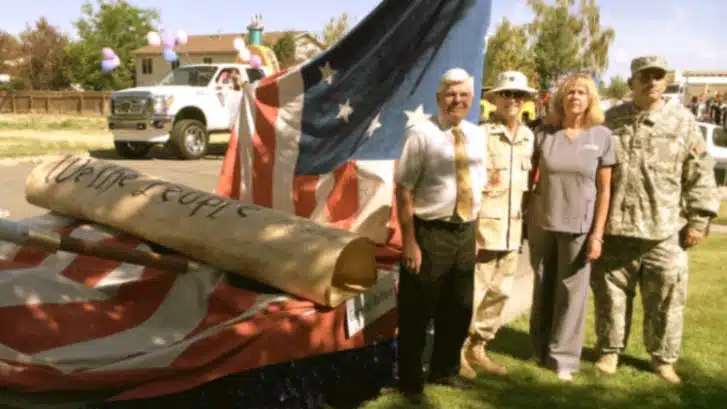 Veterans and service members with a folded flag beside a truck