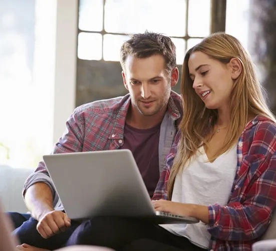 Couple looking at a laptop together on a sofa