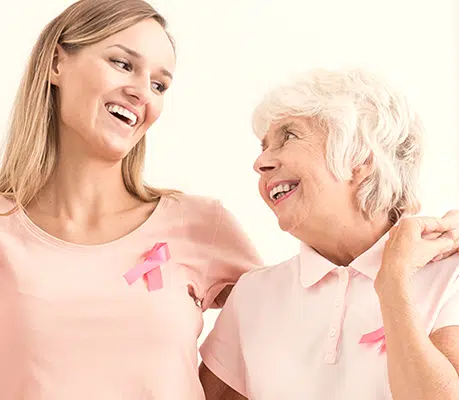 Young woman and an older woman in pink wearing breast cancer ribbons