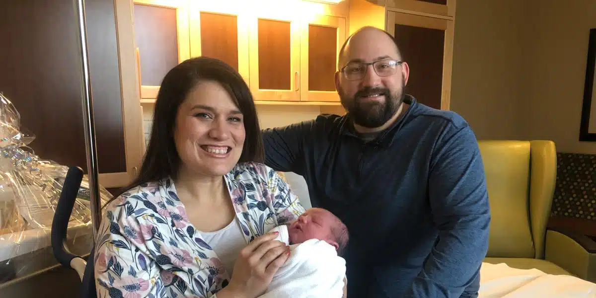 Parents holding their newborn together in a hospital room
