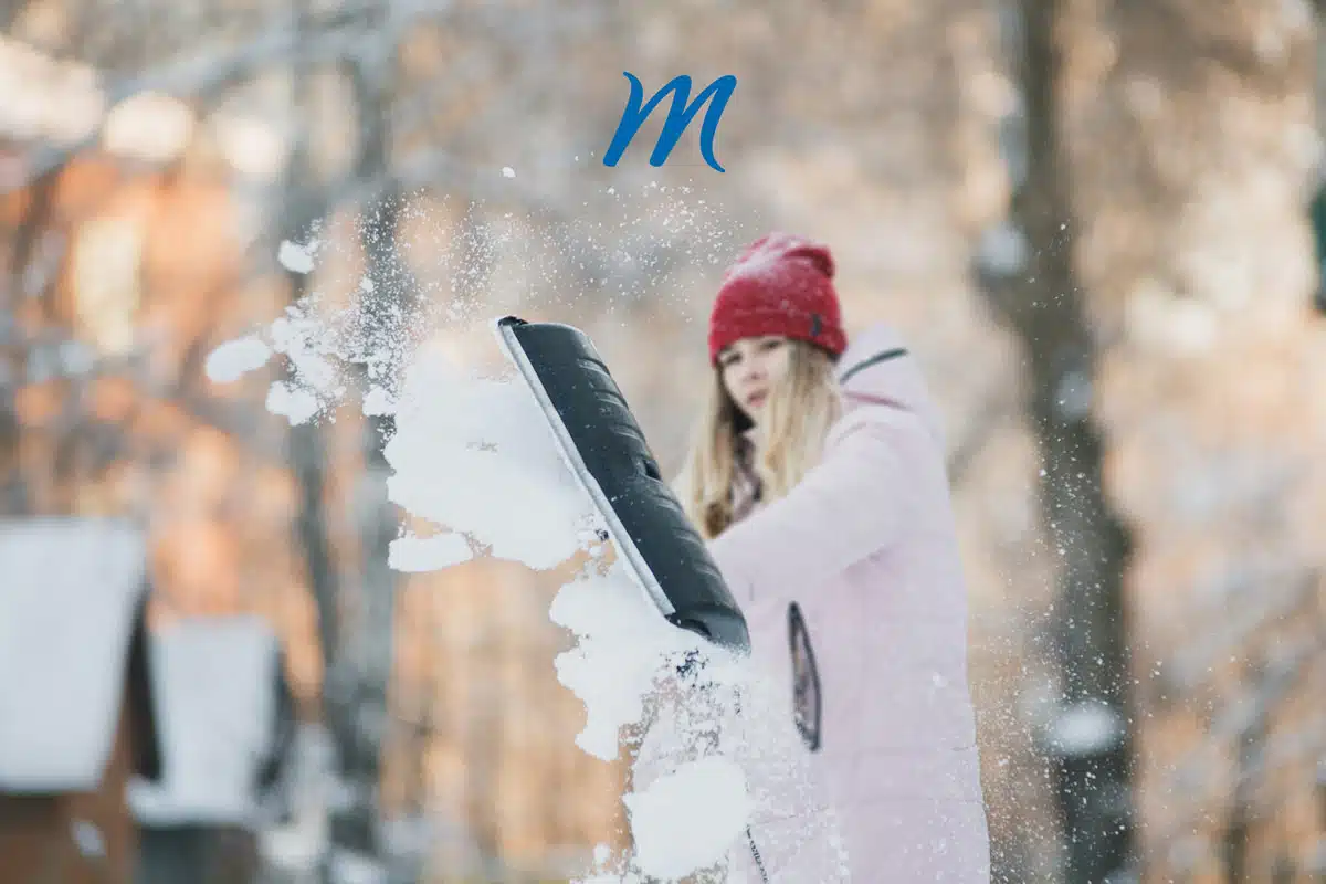 Woman in a red beanie throwing snow, with the Madison Memorial logo