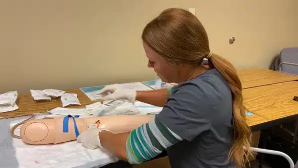 Student practicing a procedure on a training manikin arm