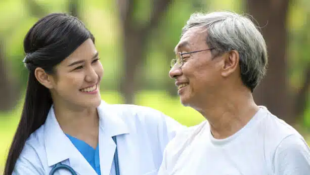 Nurse walking arm in arm with an older man outdoors