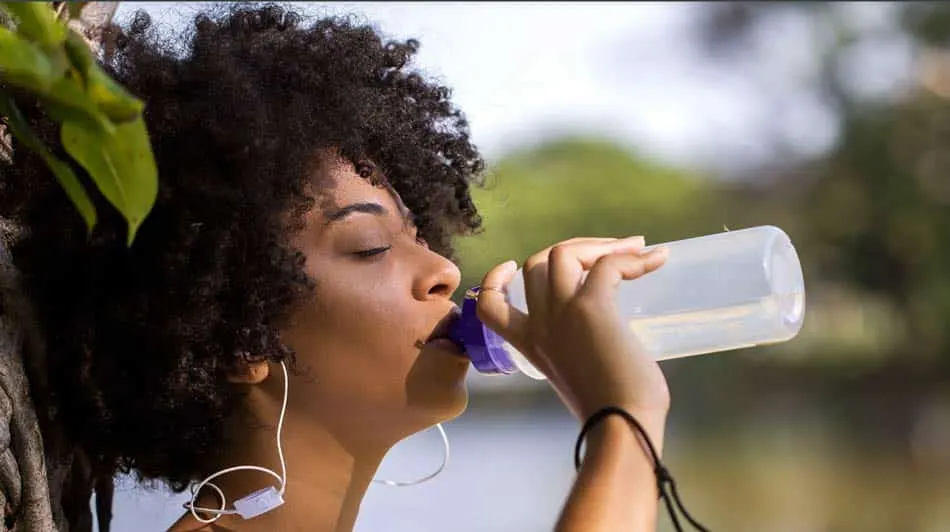 Woman drinking from a water bottle after exercising outdoors