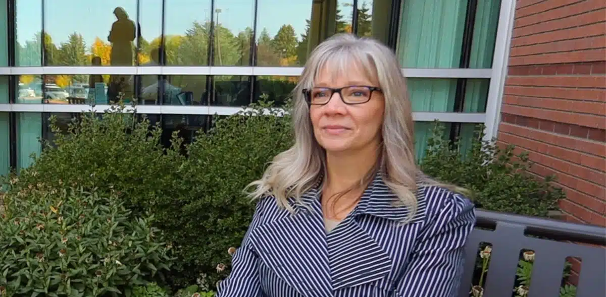 Madisonhealth staff portrait: woman with grey hair and glasses outside the hospital