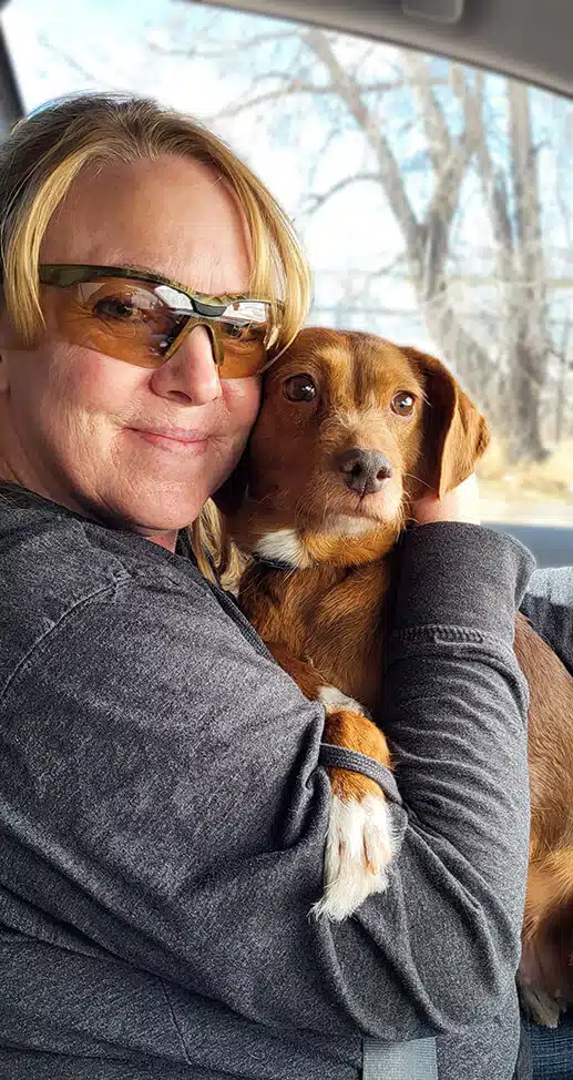 Woman in sunglasses hugging her dog in a car