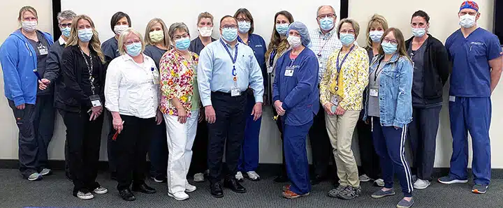 Masked hospital staff lined up together for a group photo