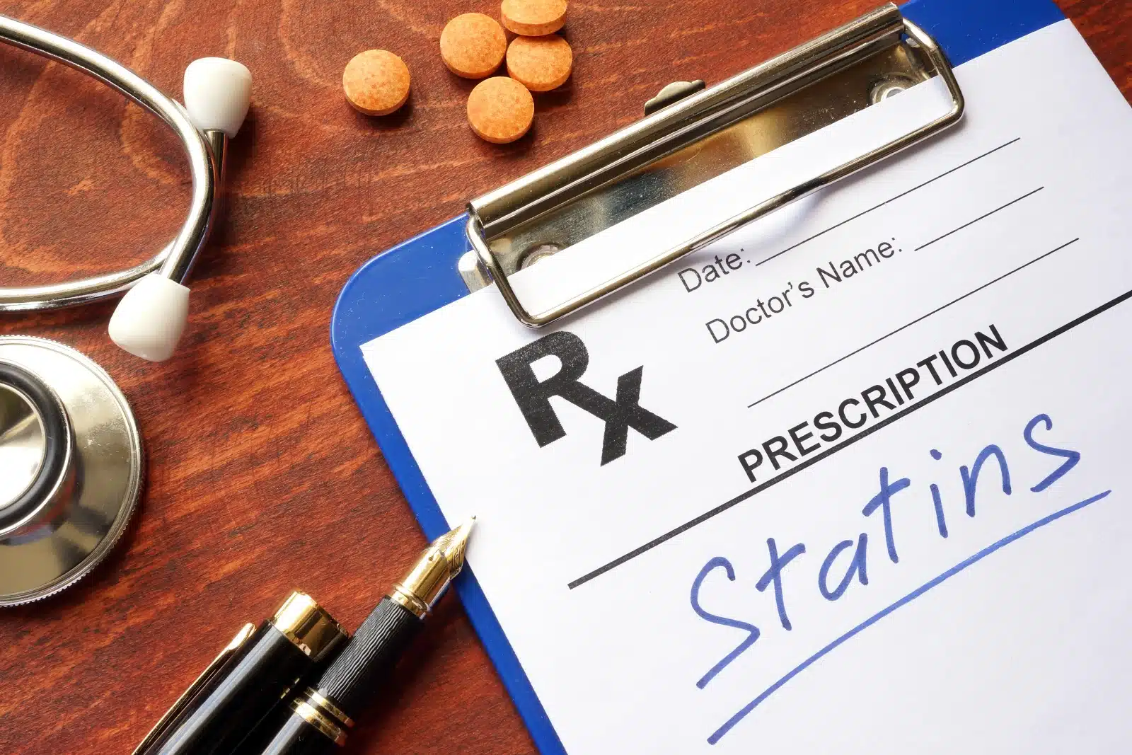 Prescription pad with Statins written on it beside a stethoscope and tablets
