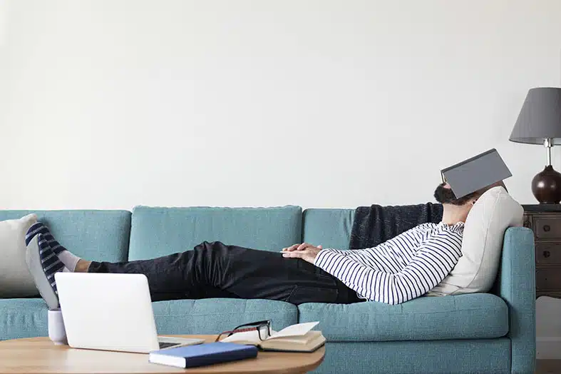 Person asleep on a sofa with an open book over their face