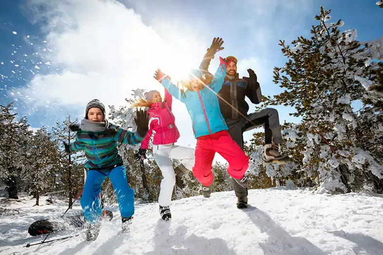 Family playing together in the snow among evergreen trees