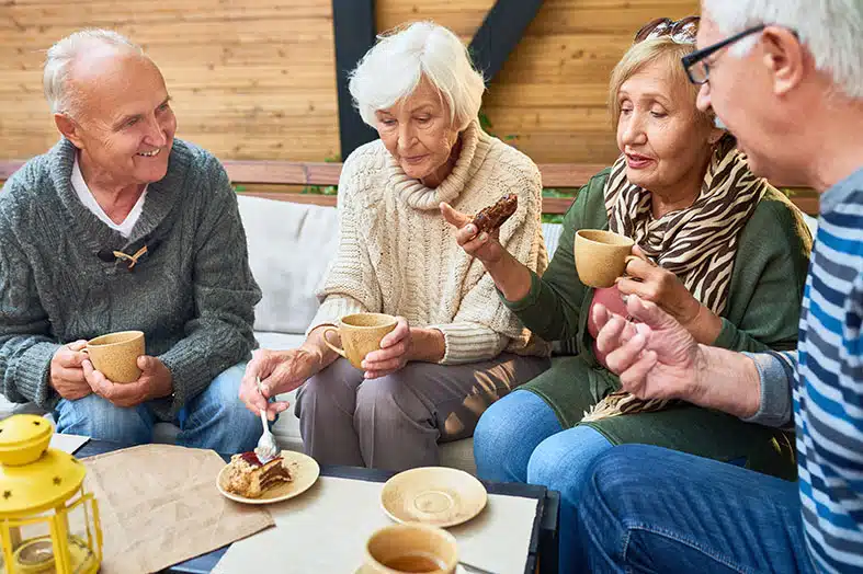 Group of older friends sharing coffee and cake together