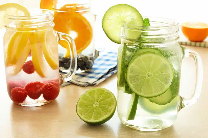 Mason jars of fruit-infused water with lemon, lime, raspberries and blueberries