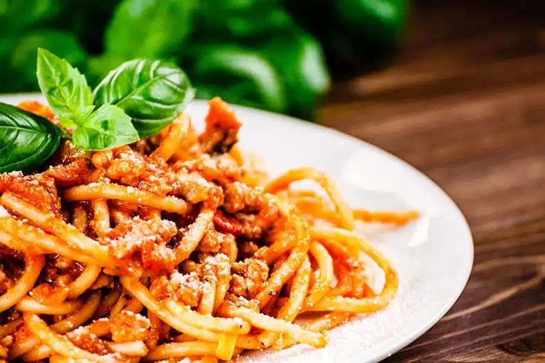 Plate of spaghetti in tomato sauce topped with fresh basil