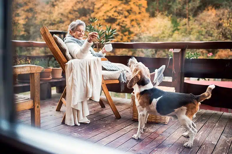 Older woman relaxing on a deck with her dog on an autumn afternoon